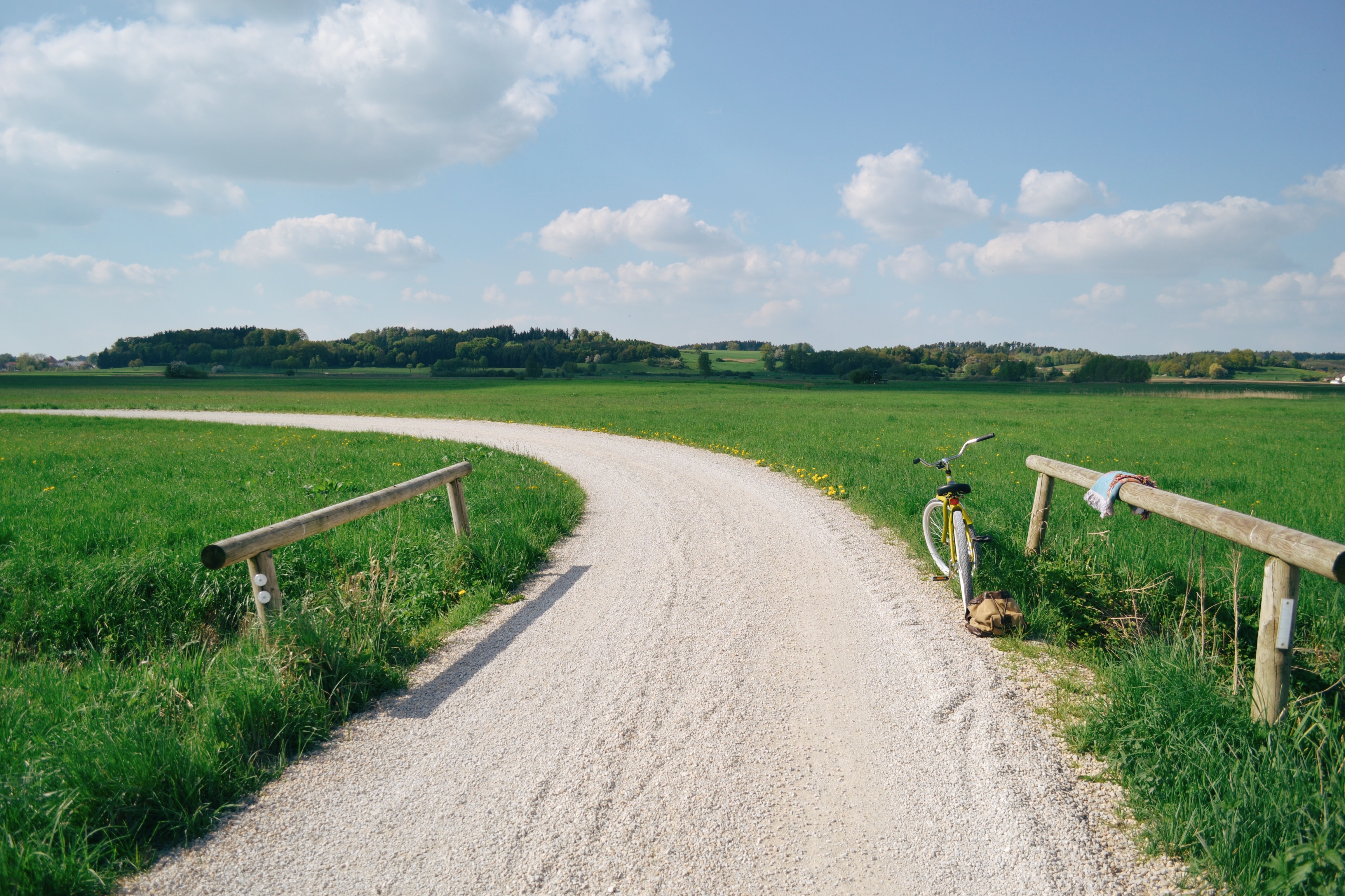 dirt road in the spring in germany with grass fields on both sides and a bicycle parked on the side of the road
