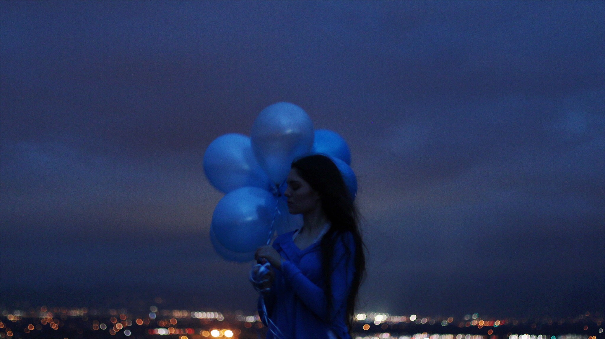 Young women in dusk with blue ballons in hand 1