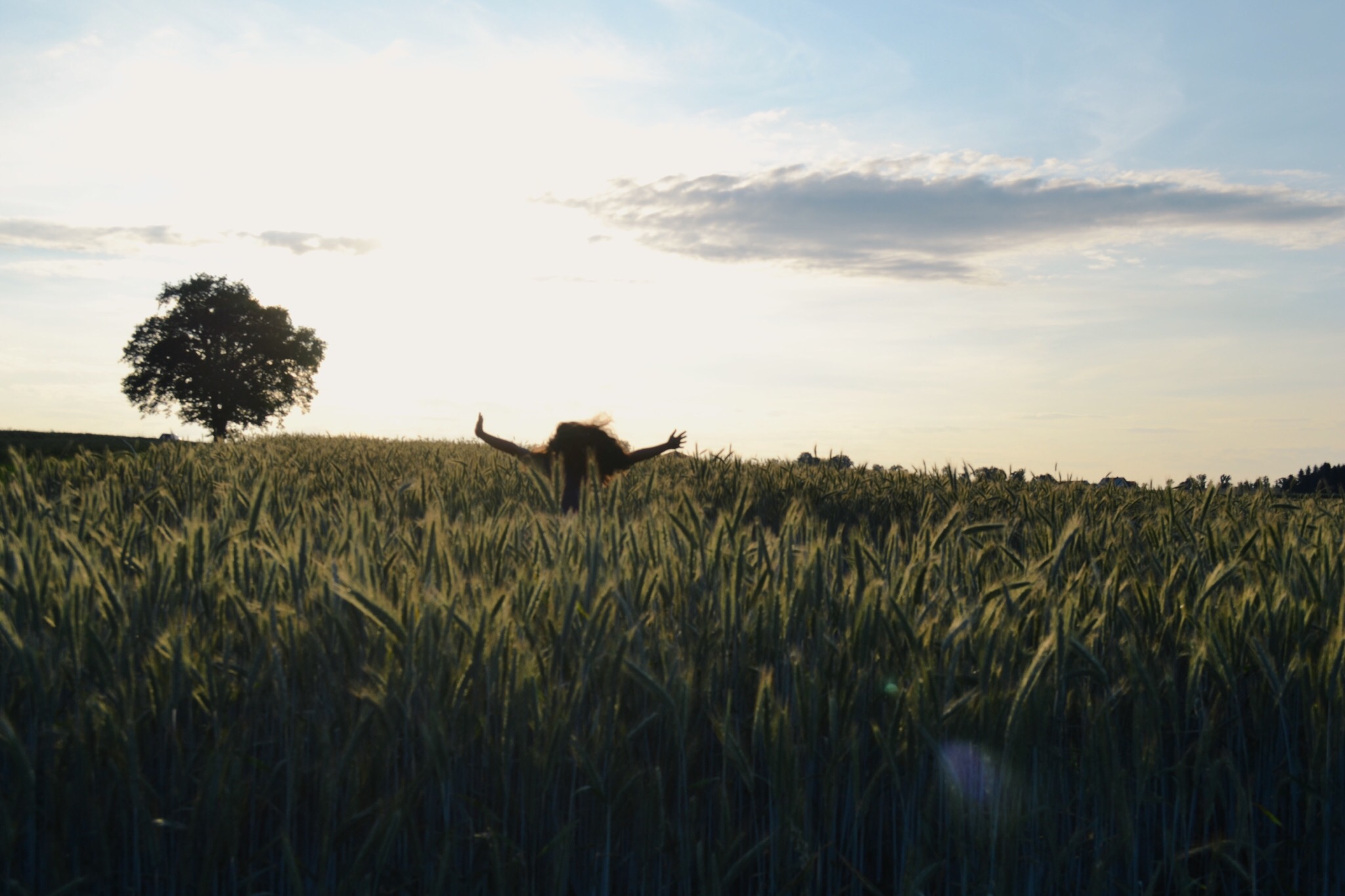 Young women running in a tall grass field with her hands up