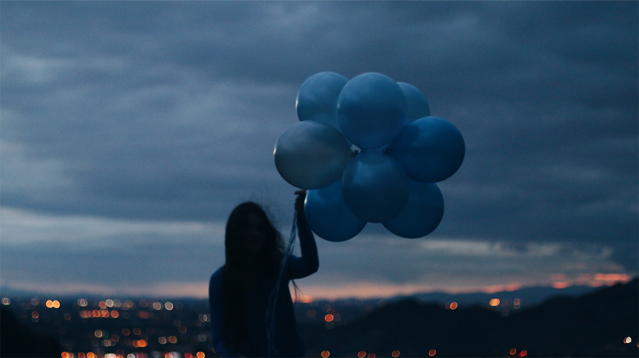 Young women in dusk with blue ballons in hand 2