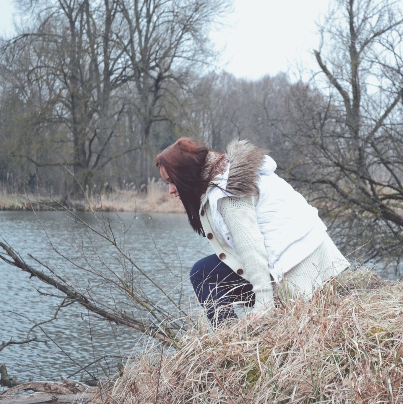 Young women sitting on the river bank in winter clothing