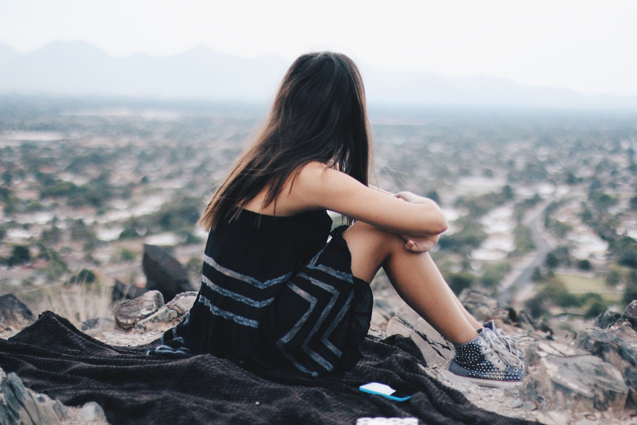 Young women sitting on the mountain with her face turned away from the camera