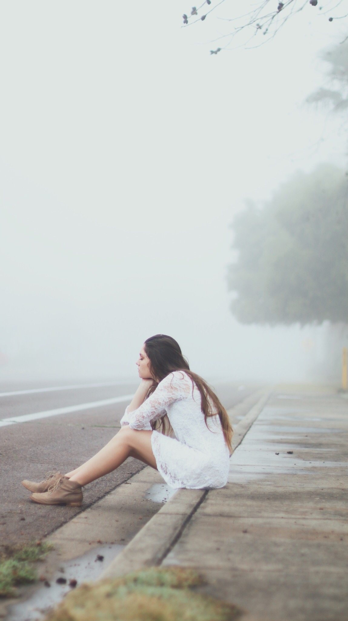 Young women in white dres sitting on the side of the road