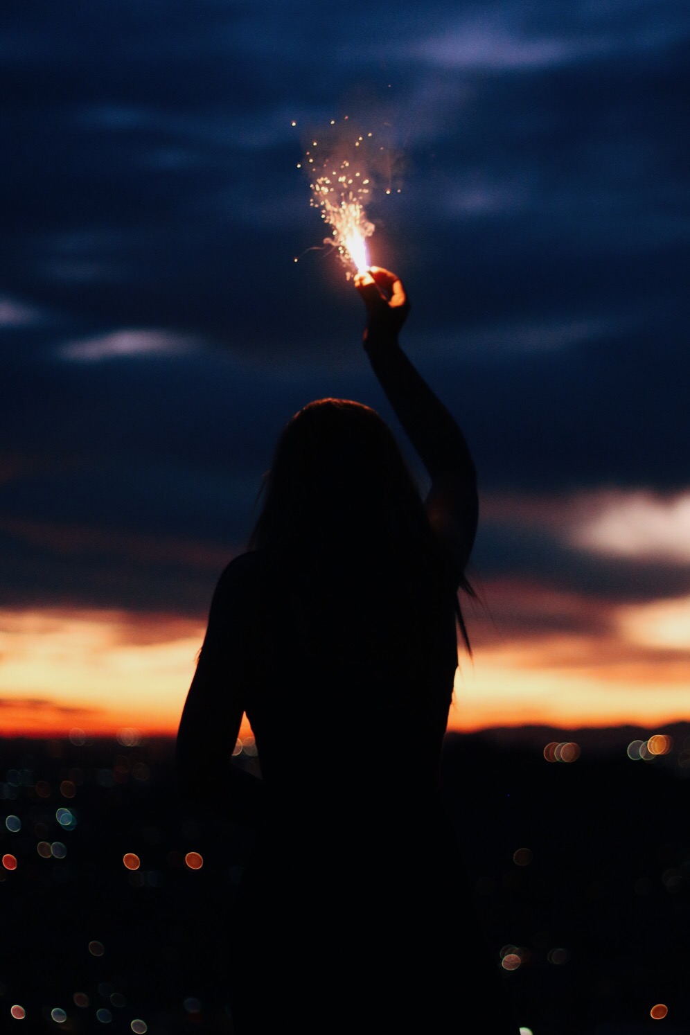 Young women in the sunset with a sparkler in the air