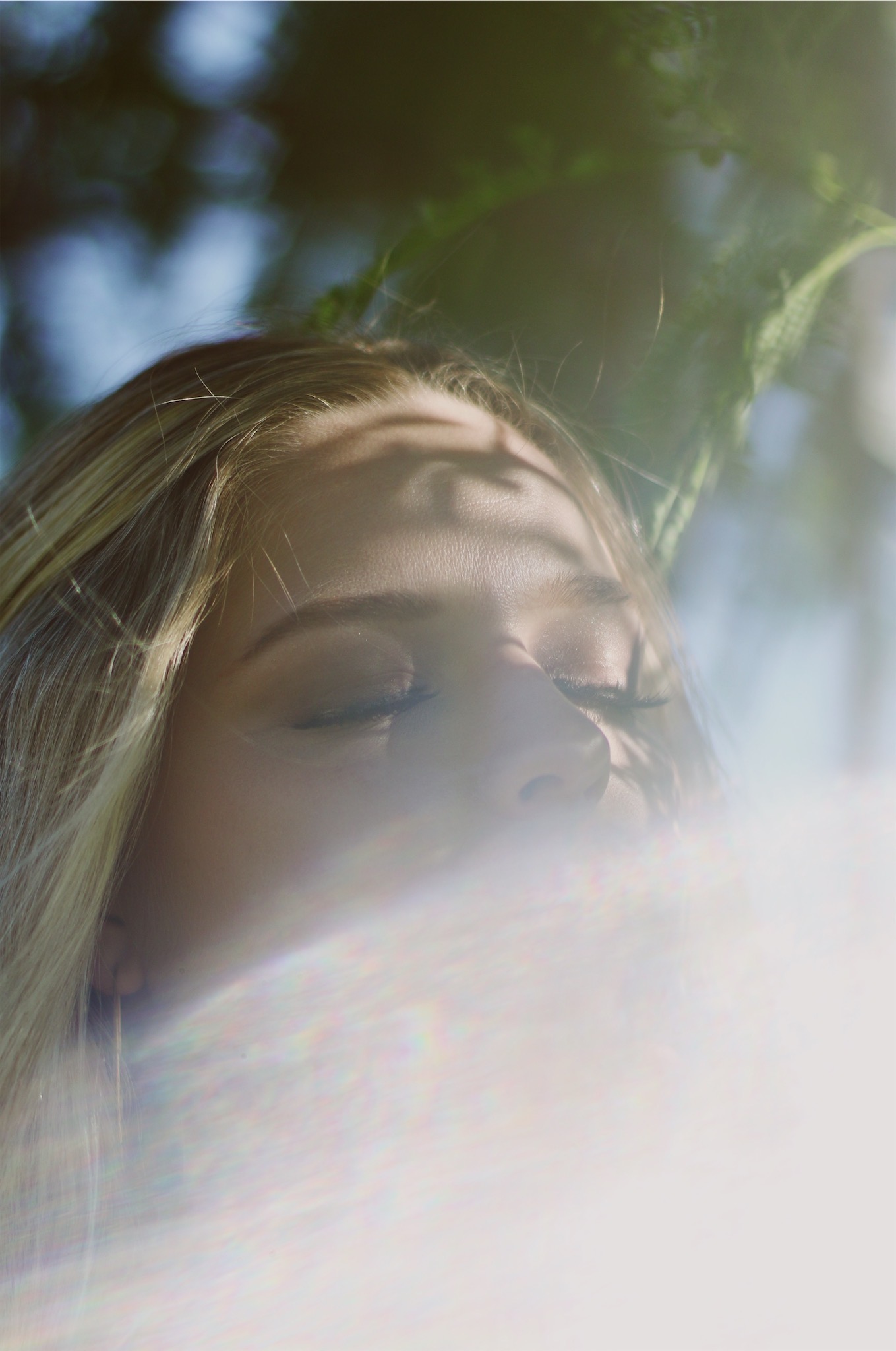 Young women under a tree with the sun glaring in the lense 2
