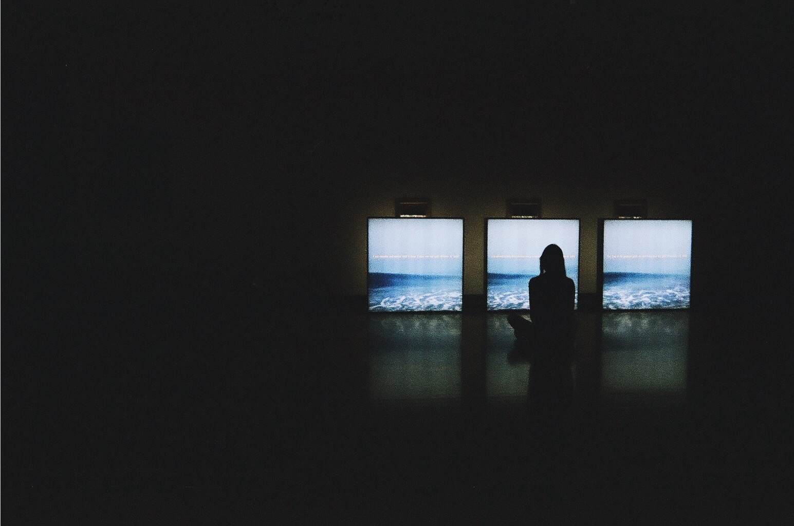Young women facing away form camera looking out the window shot on film