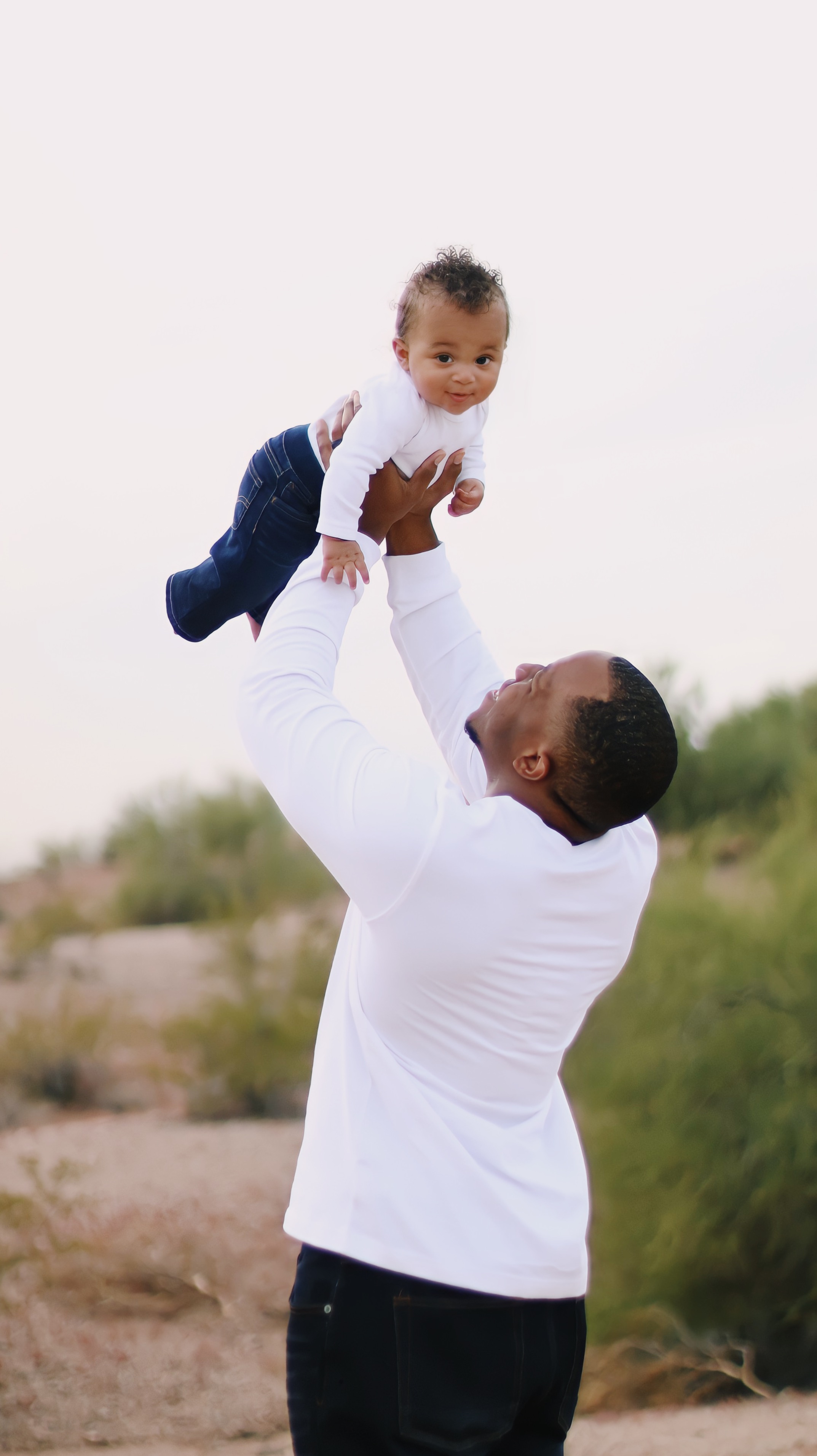 Father and child throwing baby in the air on a mountain