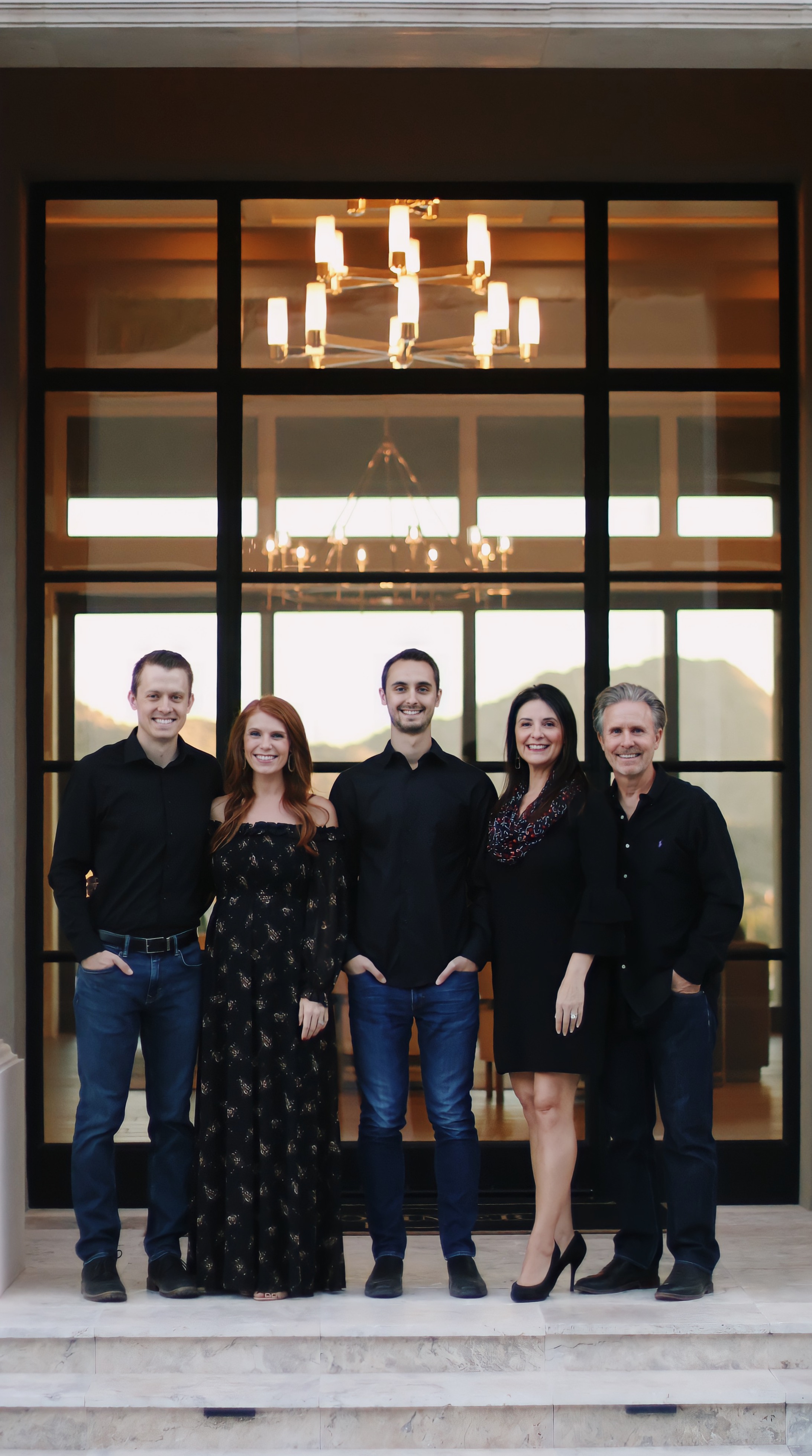 Family of five standing in front of large windows