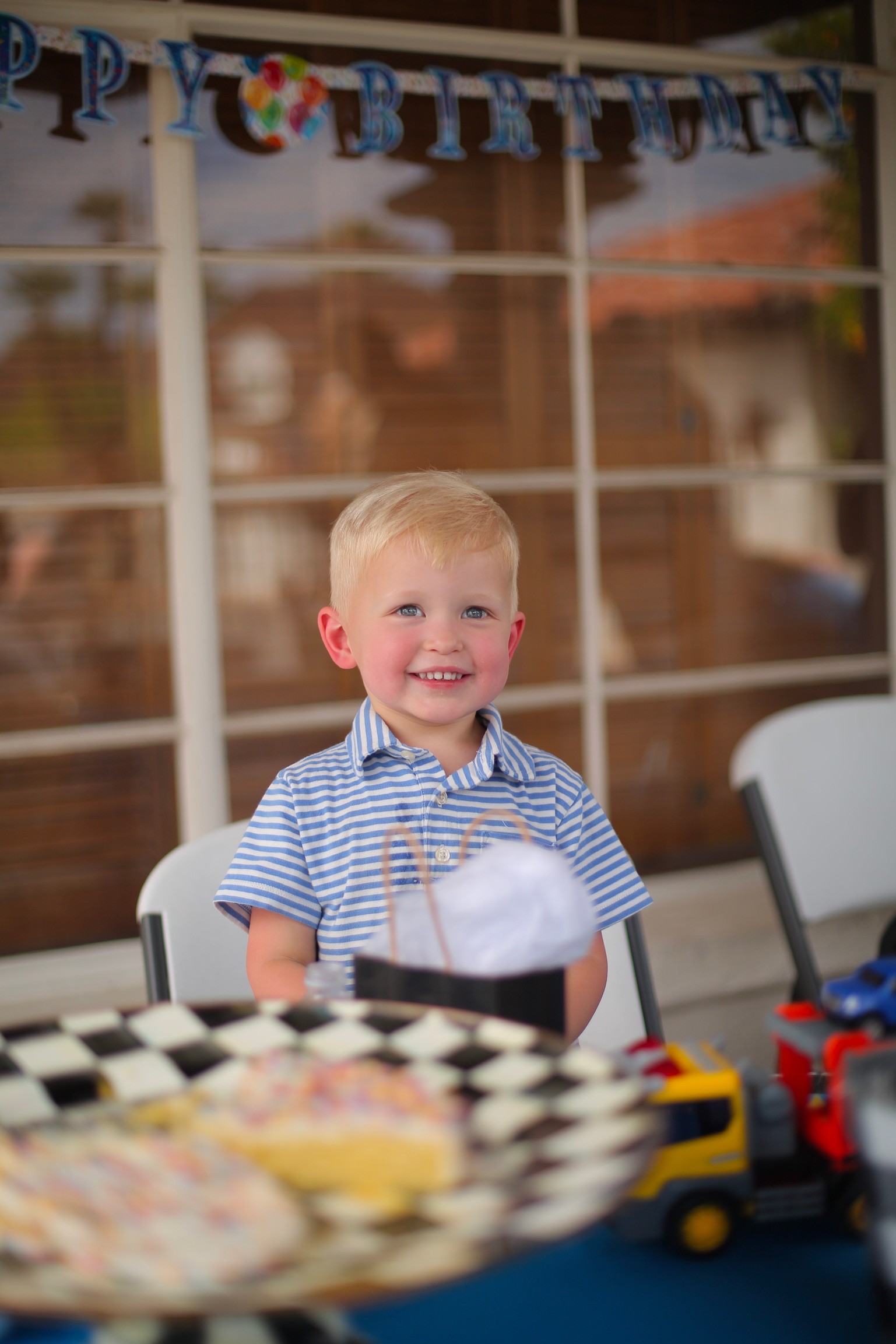 close up of a boy with blonde hair and a blue dress shirt smiling at the camera