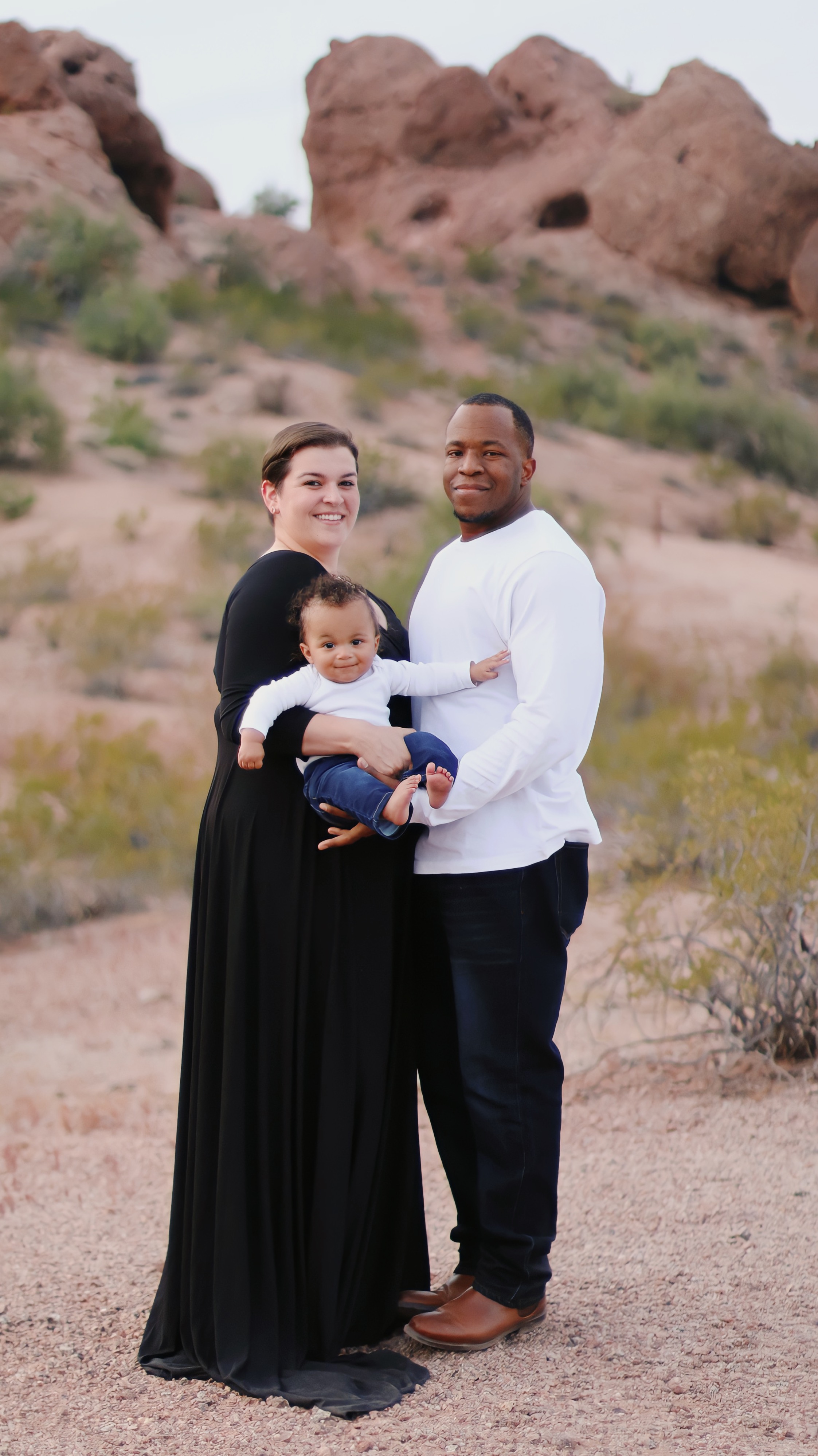 family of three with the baby held in the middle between the parents