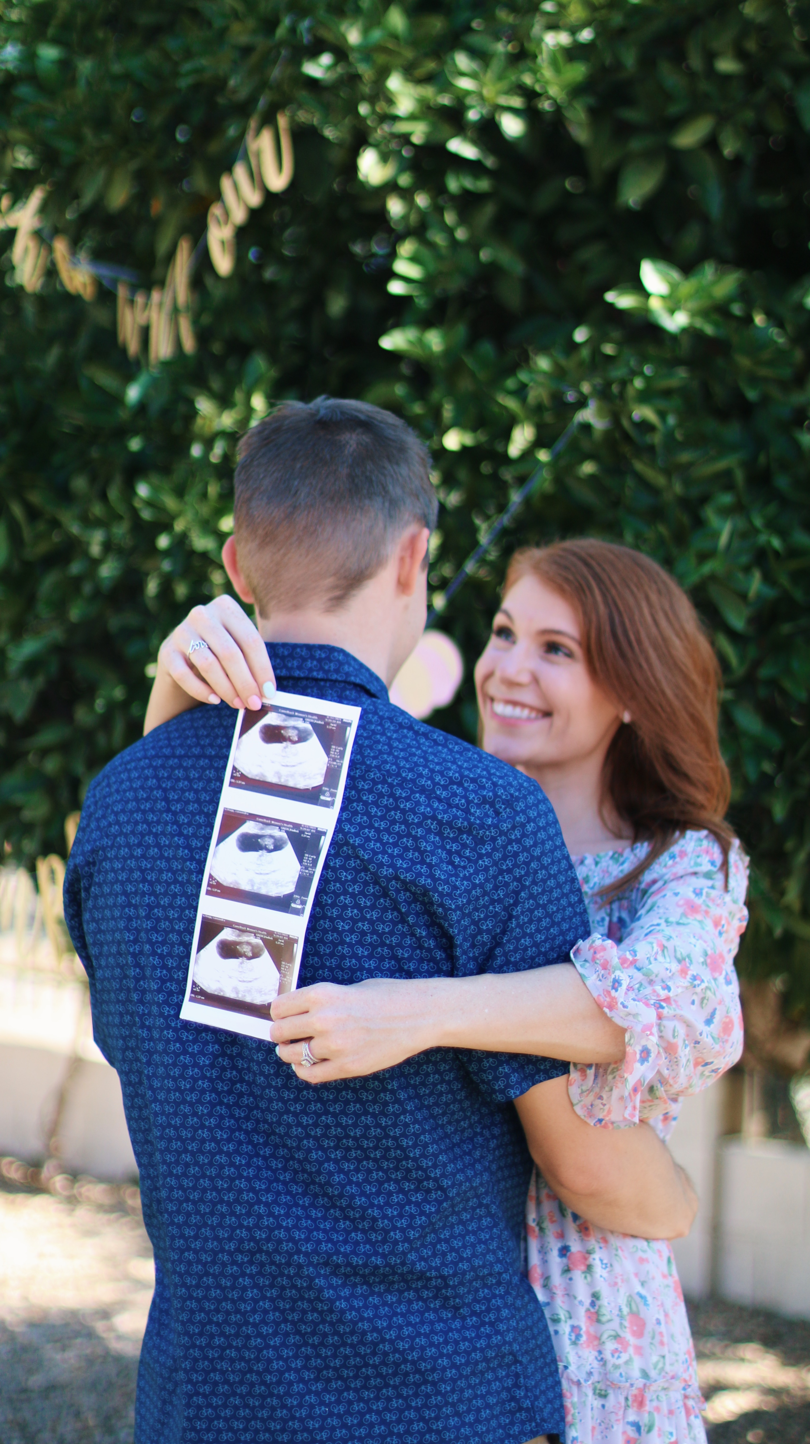 pregnancy annoucement with the ultrasound picture placed on the back of the mans shoulder