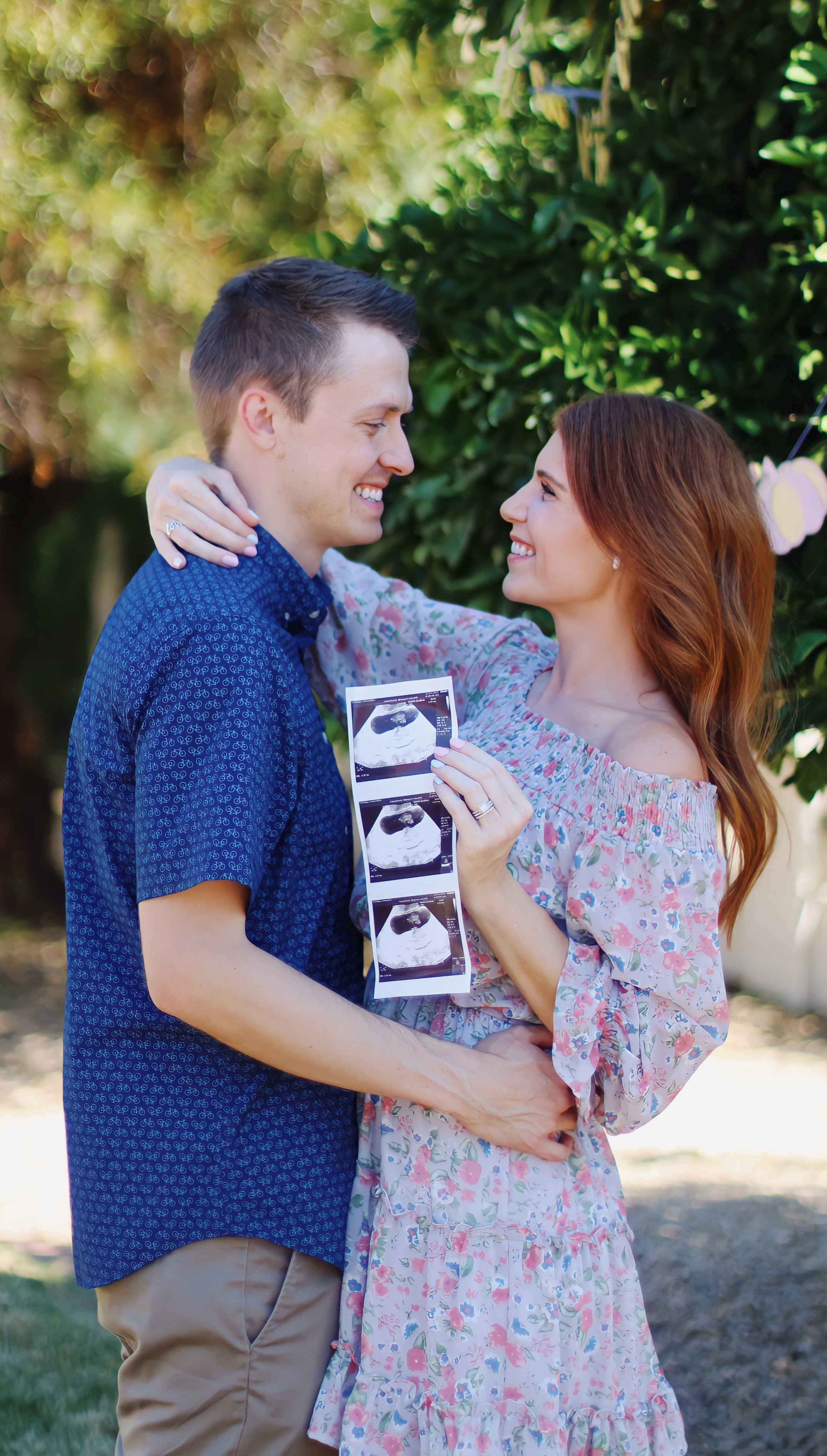 pregnancy announcement with the ultrasound picture held in the air between the parents